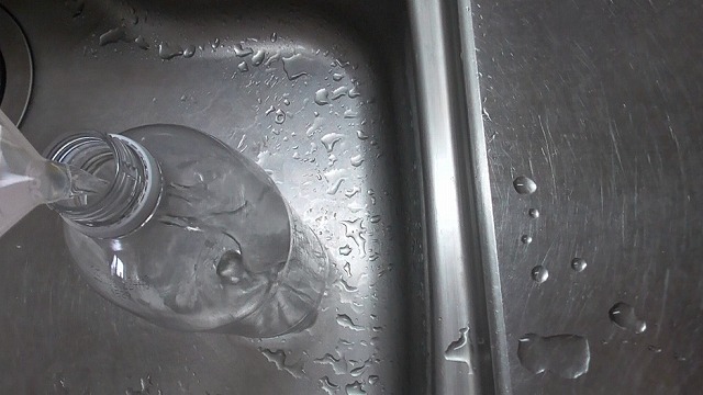 計量カップの水道水をペットボトルに注ぐ