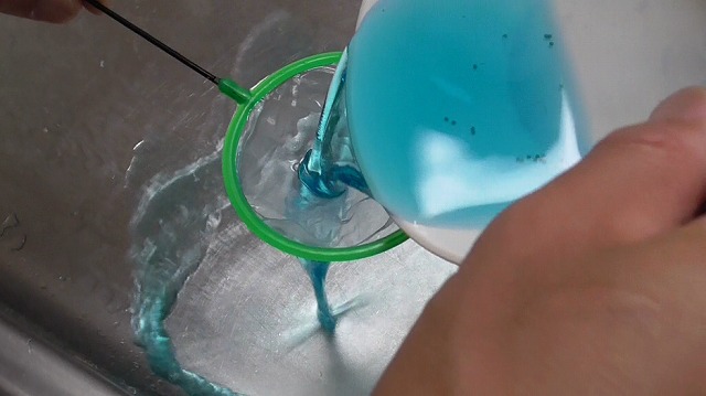 メダカの卵を入れたメチレンブルー水溶液を捨てる様子