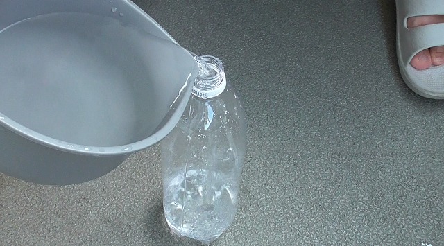 容器の中の水をペットボトルに注ぐ様子