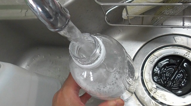 豆乳を注いだ後のペットボトルに浄水を入れる様子